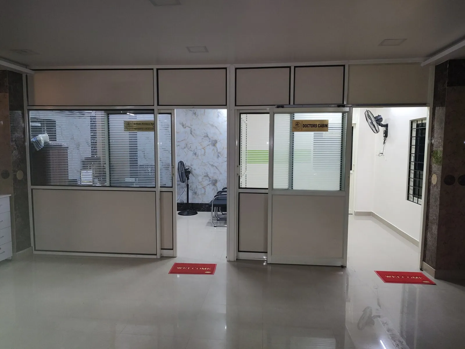 Brightly lit clinical corridor connecting consultation cabins and operatory rooms