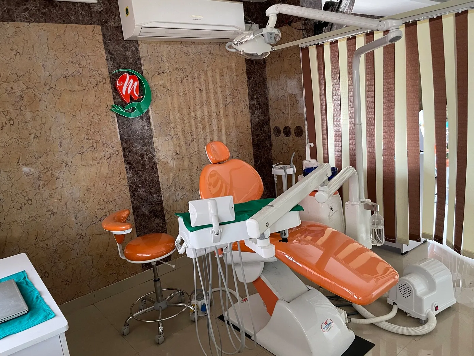 Full operatory treatment suite featuring orange dental chair and backlit Myla logo wall